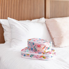 Load image into Gallery viewer, Bumkins Packing Cube 2 Pack: Boots rests stacked on a bed, surrounded by white and beige pillows in the background.
