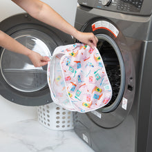 Load image into Gallery viewer, A person holds a Bumkins Packing Cube 2 Pack: Boots in front of an open front-loading washing machine.
