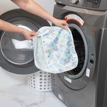 Load image into Gallery viewer, A person holds a Bumkins Packing Cube 2 Pack: Aloha Stitch in front of an open washing machine next to a white laundry basket.
