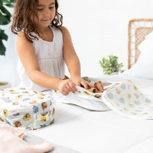 Load image into Gallery viewer, A girl in a white dress packs clothes into a Bumkins Packing Cube 2 Pack: Winnie + Friends on a bed; a plant is in the background.
