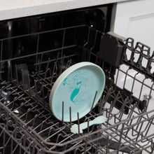 Load image into Gallery viewer, Bumkins Silicone Plate + Spoon Set: Disney Princess Ariel sits in the top rack of an open dishwasher.
