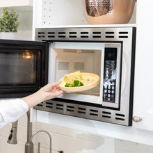 Load image into Gallery viewer, A person places Bumkins Silicone Plate + Spoon Set: Disney Winnie the Pooh filled with food into an open microwave.
