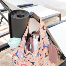 Load image into Gallery viewer, Bumkins Packable Tote Bag: Yoga Pals, made of waterproof fabric, hangs on a chair by the pool, holding a yoga mat, bottle, and towel.
