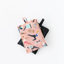 Load image into Gallery viewer, Bumkins Packable Tote Bag: Yoga Pals, folded in its pocket, is shown stacked on top of another bag on a white background.
