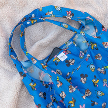 Load image into Gallery viewer, Close-up of Bumkins Packable Tote Bag: Mickey &amp; Friends Forever on a beige blanket with a smartphone in the pocket.
