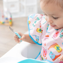 Load image into Gallery viewer, Close-up of a child in a high chair wearing a Bumkins Ruffle Apron Bib: Boots holding a fork, with blurred toys in the background.
