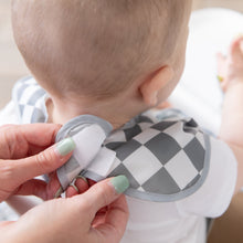 Load image into Gallery viewer, Close-up of a person adjusting the hook-and-loop closure of a Bumkins SuperBib® 3 Pack: Palms + Check on a seated baby.
