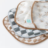 Close-up of Bumkins SuperBib® 3 Pack: Palms + Check stacked on a white background, with focus on the bottom pocket.
