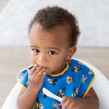 Load image into Gallery viewer, A toddler in a blue Bumkins SuperBib® 3 Pack: Mickey &amp; Friends MVP eats with a spoon, wearing a curious expression.
