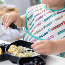 Load image into Gallery viewer, A toddler enjoys pasta and berries with a spoon from a divided tray, wearing a colorful Bumkins SuperBib® 3 Pack: Mickey &amp; Friends MVP.
