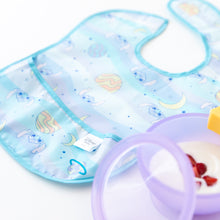 Load image into Gallery viewer, A Bumkins SuperBib® 3 Pack: Stitch Star-ring Up Trouble lays flat next to a purple bowl filled with yogurt and berries.
