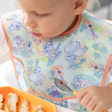Load image into Gallery viewer, A toddler in a Bumkins SuperBib® 3 Pack: Stitch Star-ring Up Trouble, focused on eating from an orange plate with a spoon.
