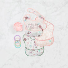 Load image into Gallery viewer, Bumkins SuperBib® 3 Pack: Love You Bunches lays next to a pink bowl and spoon set, and pastel teething rings on a marble background.
