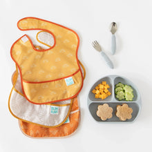Load image into Gallery viewer, Bumkins SuperBib® 3 Pack: Desert Boho lays overlapped on a white background next to a gray divided plate of food and gray utensils.

