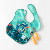 A spoon and fork with yellow handles lay partially on a Bumkins SuperBib® 3 Pack: All Together Now on a white background.