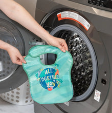 Load image into Gallery viewer, A person holds a Bumkins SuperBib® 3 Pack: All Together Now in front of an open front-loading washing machine.
