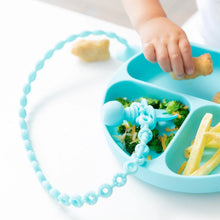 Load image into Gallery viewer, Close-up of a child reaching for food on a blue plate, with a toddler fork attached to a Bumkins Silicone Accessory Tether 2-Pack: Blue.
