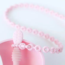 Load image into Gallery viewer, Close-up of a Bumkins Silicone Accessory Tether 2-Pack: Pink attached to a spoon in a bowl on a white background.
