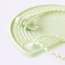 Load image into Gallery viewer, Close-up of a Bumkins Silicone Accessory Tether 2-Pack: Sage with a silicone placemat and fork on a white background.
