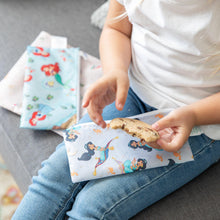 Load image into Gallery viewer, A child on a couch holds a half-eaten cookie, with Bumkins Reusable Snack Bag, 3-Pack: Princess Magic, Ariel, and Jasmine on their lap.
