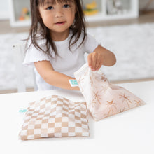 Load image into Gallery viewer, A child opens Bumkins Reusable Snack Bag, Large 2 Pack: Palm Check at a white table.
