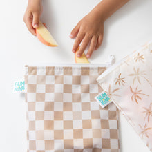 Load image into Gallery viewer, Close-up of a child placing apple slices into a Bumkins Reusable Snack Bag, Large 2 Pack: Palm Check on a white table with another bag nearby.
