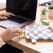Load image into Gallery viewer, A hand reaches for popcorn from a Roamio by Bumkins Bumkins Reusable Snack Bag, Large 2 Pack: Double Check next to a laptop on a desk.
