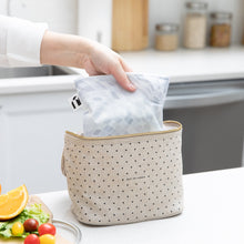 Load image into Gallery viewer, A hand places a Roamio by Bumkins Reusable Snack Bag, Large 2 Pack: Disco Boots into a lunch bag on a counter next to fruit &amp; veggies.
