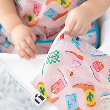 Load image into Gallery viewer, Close-up of a Roamio by Bumkins Reusable Snack Bag, Large 2 Pack: Disco Boots held by a child wearing a matching bib.
