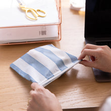 Load image into Gallery viewer, Close-up of hands holding a Roamio by Bumkins Reusable Snack Bag, Large 2 Pack: Coastal near a laptop and papers on a desk.
