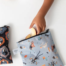 Load image into Gallery viewer, A child's hand reaches into a Bumkins Reusable Snack Bag, Large 2 Pack: Everyday Is Halloween on a white table, holding fresh apple slices.

