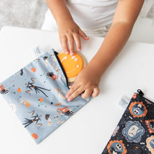 Load image into Gallery viewer, A child puts a smiley face cookie in a Bumkins Reusable Snack Bag, Large 2 Pack: Everyday Is Halloween at a white table.

