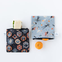 Load image into Gallery viewer, Bumkins Reusable Snack Bag, Large 2 Pack: Everyday Is Halloween lays on a white background. A sandwich peeks from one bag, oranges from the other.
