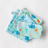 Bumkins Reusable Snack Bag, Large 2-Pack: Ocean Life & Whale Tail lays underneath other similar bags on a white background.