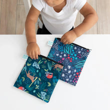 Load image into Gallery viewer, A child in a white shirt grasps Bumkins Reusable Snack Bag, Large 2-Pack: Jungle &amp; Animal Prints on a white table.
