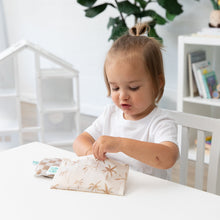 Load image into Gallery viewer, A toddler opens a Bumkins Reusable Snack Bag, Small 2 Pack: Palm Check at a white table with another bag nearby; a plant &amp; shelves sit behind.
