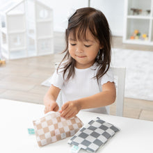 Load image into Gallery viewer, A young girl with a white bow opens a Bumkins Reusable Snack Bag, Small 2 Pack: Double Check at a white table with another bag nearby.
