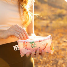 Load image into Gallery viewer, Close-up of a person reaching for snacks from a Roamio by Bumkins Reusable Snack Bag, Small 2 Pack: Disco Boots in golden sunlight.
