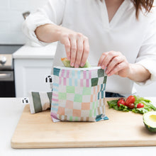 Load image into Gallery viewer, A person places a wrap in a Roamio by Bumkins Reusable Snack Bag, Large 2 Pack: Motley Club on a cutting board near veggies.
