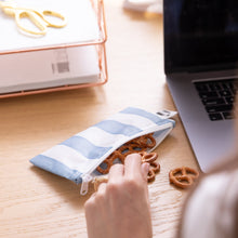 Load image into Gallery viewer, A hand reaches for pretzels from a Roamio by Bumkins Reusable Snack Bag, Small 2 Pack: Coastal on a desk next to a laptop.
