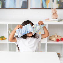 Load image into Gallery viewer, A child holds Bumkins Reusable Snack Bag, Small 2 Pack: Stitch Star-ring Up Trouble in front of their face at a white table.
