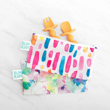 Load image into Gallery viewer, Orange toddler utensils peek from Bumkins Reusable Snack Bag, Small 2-Pack: Watercolor &amp; Brush Strokes on a marble background.
