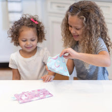 Load image into Gallery viewer, Two curly-haired girls smile as they open Bumkins Reusable Snack Bag, Small 2-Pack: Rainbows &amp; Unicorns at a white table.
