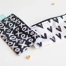 Load image into Gallery viewer, Close-up of Bumkins Reusable Snack Bag, Small 2-Pack: XOXO &amp; Hearts on a white background with cereal pieces.
