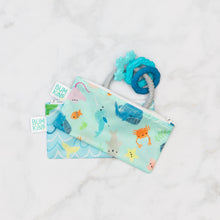 Load image into Gallery viewer, Bumkins Silicone Teething Charms: Blue peeks out of two stacked ocean-themed pouches on a marble background.
