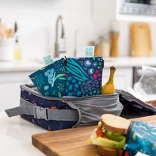 Load image into Gallery viewer, Bumkins Reusable Snack Bag, Small 2-Pack: Jungle &amp; Animal Prints sits in a lunch bag with a banana, next to a sandwich in a kitchen.
