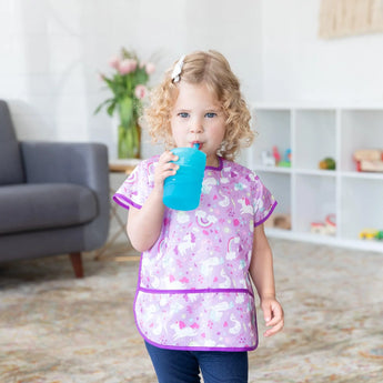 A child with curly hair in a unicorn bib drinks from a Bumkins Silicone Straw Cup with Lid: Blue.