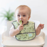 A baby in a green llama bib sits in a high chair, placing a green Bumkins Silicone Dipping Spoons 3 Pack: Taffy in their mouth.
