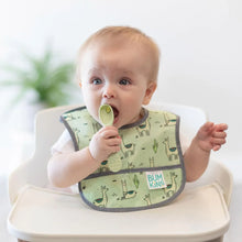 Load image into Gallery viewer, A baby in a green llama bib sits in a high chair, placing a green Bumkins Silicone Dipping Spoons 3 Pack: Taffy in their mouth.
