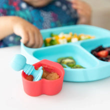 Load image into Gallery viewer, Close-up of a child explores baby-led from a blue divided plate, with a Bumkins Silicone Chewtensils®: Blue in a red heart-shaped cup.
